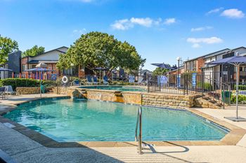 A large outdoor swimming pool surrounded by a fence and trees.
